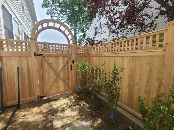 Natural cedar privacy fence with a lattice top and an arched arbor over a cedar gate