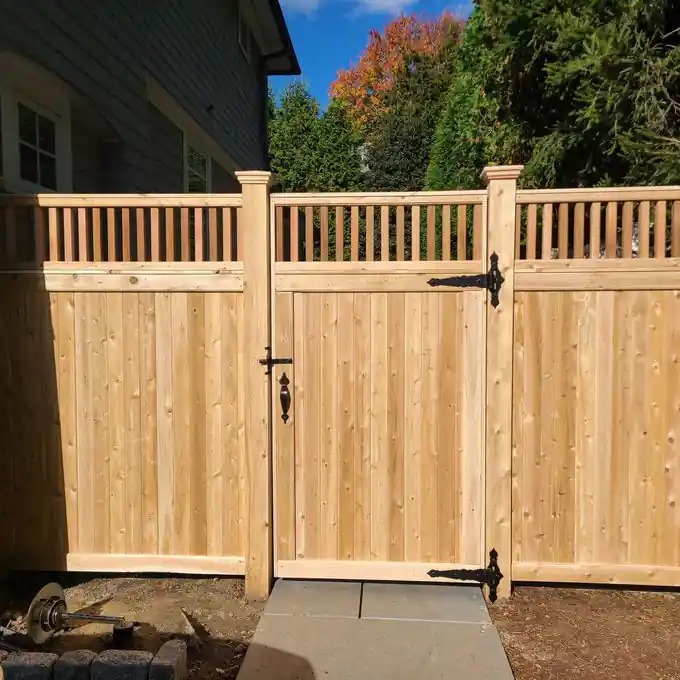 Solid cedar double driveway gate with a spindle top and black strap hinges
