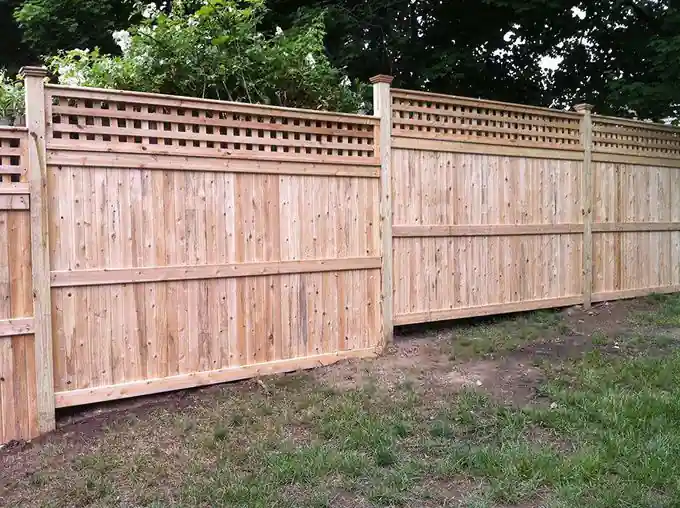 Long run of cedar board privacy fence with a square lattice topper