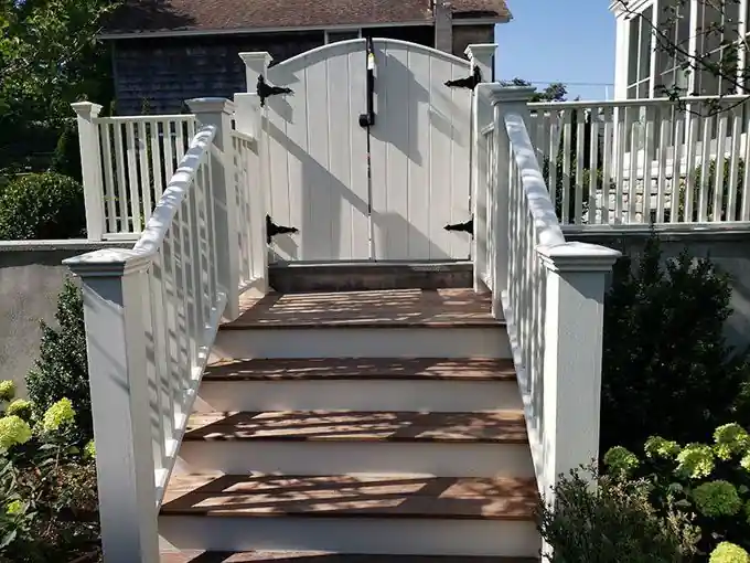 White arched-top gate at the head of a stair with matching vinyl railing